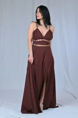 Vestido largo de fiesta color marrón chocolate, con breteles finos, escote en V y tajo lateral. Presenta detalle de doble abertura en la cintura con apliques de argollas doradas.