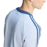 Remera de fútbol Adidas de la selección de Italia, de color celeste con cuello redondo y detalles en azul marino en el cuello y las mangas. Presenta el logotipo de Adidas Originals y el escudo de la Federación Italiana de Fútbol bordados en el pecho, junto con las clásicas tres tiras de la marca sobre los hombros.