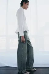Camisa de popelín de algodón con cuello solapa, manga larga con puños y bajo con diseño peplum. Presenta cierre frontal oculto con botones.