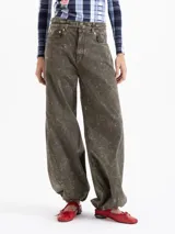Pantalón wide leg de denim con lavado efecto gastado en tono verde oliva. Presenta cinco bolsillos, cierre frontal con botón y un cinturón integrado del mismo tejido con doble hebilla metálica.