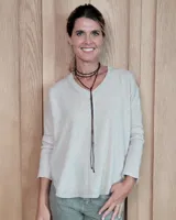 Sweater de punto color beige, con cuello en V, manga larga con puños acanalados y diseño holgado.