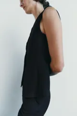 Chaleco negro entallado de Zara Woman Collection, con escote pico, sin mangas, forro interior a tono, bajo asimétrico y cierre frontal con botones.
