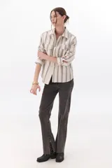 Pantalón de jean gris oscuro, de corte recto, tiro alto y tajos laterales en el ruedo.