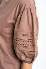 Remera negra de algodón con mangas cortas abullonadas que presentan detalles de encaje bordado y calado en los extremos.