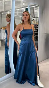 Vestido largo de satén azul marino, con tirantes finos, escote recto y tajo lateral en la pierna.