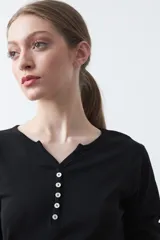 Remera de manga larga color beige, confeccionada en algodón, con escote en V y cartera corta de botones blancos.