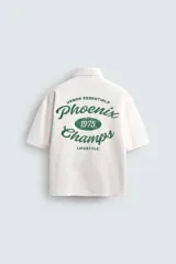 Camisa de algodón con estructura canvas, color rojo lavado, de corte relajado (relaxed fit) y manga corta. Posee cuello solapa, dos bolsillos de plastrón en el pecho y cierre frontal de botonadura. Presenta bordado y estampado de texto a contraste en el delantero.