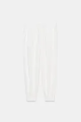Pantalón blanco de tiro alto con cintura ajustable mediante cordón y puños elásticos en los tobillos. Presenta bolsillos laterales ocultos en la costura.