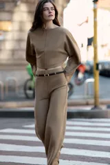 Pantalón palazzo de tiro alto color beige, con pierna ancha y cinturón fino de efecto piel negro con hebilla metálica.