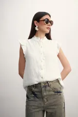 Camisa blanca sin mangas con cuello mao y volados.