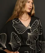 Blusa negra con estampado de hojas en color crema, escote en V y mangas 7/8.