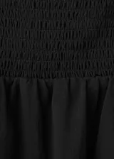 Vestido midi negro con escote halter, diseño sin mangas y detalle drapeado en la cintura.