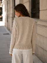 Cardigan de punto color beige, de manga larga y cuello redondo, con detalles de puntilla en el bajo y los puños, y bolsillos aplicados con trabillas decorativas en la espalda.