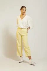 Pantalón de jean color amarillo pastel, de corte recto y tiro medio, con diseño de cinco bolsillos y cierre frontal con botón y cremallera.