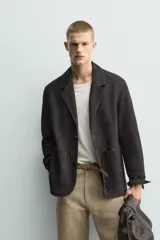 Blazer de corte relajado confeccionada en piel con acabado de ante. Presenta cuello con solapas de muesca, cierre frontal de dos botones, mangas largas y bolsillos de plastrón en la parte delantera. Destaca por sus costuras con efecto lavado que le otorgan un aspecto vintage.