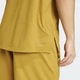 Remera deportiva Adidas de manga corta y cuello redondo, color mostaza/amarillo ocre, con un pequeño logo Adidas en relieve en el pecho. Presenta costuras reforzadas en los hombros.