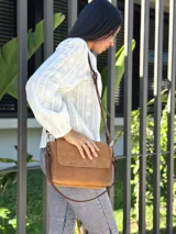 Cartera bandolera de cuero gamuzado color camel, con solapa frontal y cierre principal. Incluye dos correas desmontables, una corta y una larga regulable, y cuenta con bolsillo interior.