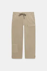 Pantalón cargo de tiro medio en color beige, con cintura ajustable mediante cordones a contraste. Presenta bolsillos delanteros, bolsillos traseros con solapa y bolsillos laterales de plastrón con solapa y botones. El bajo cuenta con detalle de trabillas y botón.