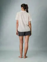 Camisa de pijama de manga corta color beige con estampado de letras negras, cuello clásico y cierre frontal con botones.