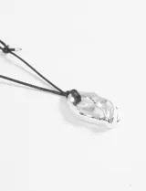 Collar de cordón negro tipo gamuza con un dije metálico de diseño irregular y orgánico en color plateado.