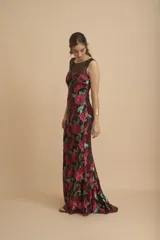 Vestido largo negro íntegramente bordado con lentejuelas en tonos fucsia y verde, con diseño floral, escote redondo y transparencias en la parte superior.