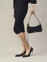 Bolso de hombro Jacquemus Le Bisou Perle, estructurado en piel lisa negra, con correa de hombro ajustable decorada con ab cuentas grandes efecto carey. Incluye logotipo metálico dorado en la parte frontal y herrajes metálicos a juego.