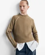 Jersey de punto color tostado con cuello alto y mangas raglán con líneas blancas decorativas en los hombros.