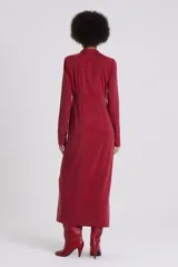 Vestido camisero largo color rojo oscuro, de manga larga y cuello camisero. Presenta un cierre frontal completo con botones oscuros y una abertura en el ruedo.