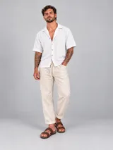 Camisa de manga corta color blanco, de corte holgado, con cuello tipo solapa y cierre frontal de botones.