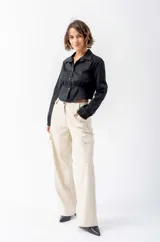 Camisa negra de corte entallado con cuello clásico y cierre frontal de botones. Presenta un diseño con elástico en la cintura que marca la silueta y mangas largas con puños elásticos.