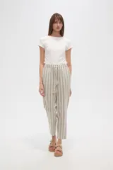 Pantalón tipo babucha de corte recto y tiro medio, con cintura elástica y cordón ajustable con borlas decorativas. Presenta un diseño de rayas verticales en tonos neutros.