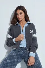Campera de punto tipo cardigan en color bordó, con cierre frontal, cuello redondo y diseño estilo universitario. Presenta el número 54 bordado en blanco en el pecho y franjas blancas en las mangas.