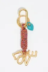Llavero con cuerpo de cabo trenzado multicolor, mosquetón y argolla metálicos dorados, dije de corazón esmaltado en color turquesa y dijes metálicos dorados que forman la palabra LOVE.