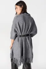 Ruana de tejido suave y envolvente en color blanco, con diseño de corte amplio y terminación de flecos en el ruedo.