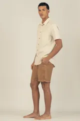 Camisa de manga corta color crema con textura, botones de madera y parche con logo.