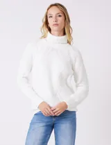 Polera de punto grueso color blanco, con cuello alto, mangas largas de corte ranglan y diseño de texturas combinadas.