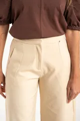 Pantalón de corte baggy y tiro medio, confeccionado en algodón peinado de color arena. Presenta diseño de pierna ancha, cierre frontal con botón y bolsillos laterales.