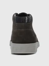 Bota urbana de caña baja confeccionada en cuero gamuzado color marrón oscuro, con cordones al tono y suela de poliuretano gris con tecnología de amortiguación.
