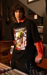 Remera de manga corta con cuello redondo y corte oversize, confeccionada en algodón premium. Presenta un estampado frontal con diseño gráfico inspirado en la banda The Prodigy, con elementos visuales que incluyen rostros, tipografía y motivos abstractos.