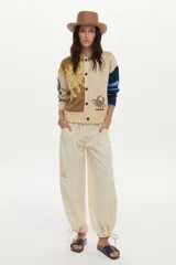 Cardigan de punto con ilustraciones en jacquard y detalle bordado en el frente, mangas largas con puños acanalados, escote redondo y cierre frontal de botones.