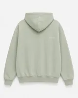 Canguro con capucha de calce oversize, confeccionado en tejido pesado color gris claro. Presenta un bordado minimalista con la palabra 'ASCEND' en la parte superior trasera, puños y ruedo acanalados.