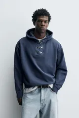 Sudadera hoodie relaxed fit color azul, confeccionada en tejido de algodón. Presenta capucha y cierre frontal con alamares metálicos, manga larga y acabados en rib.