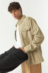 Sobrecamisa de pana color beige, con cuello clásico, cierre frontal de botones y bolsillos tipo cartera en el pecho.