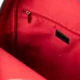 Mochila negra con detalles en rojo y blanco, confeccionada en símil cuero. Tiene un compartimento principal con cierre, un bolsillo interno con cierre y dos bolsillos abiertos, además de un bolsillo externo con cierre. Las correas son regulables y los herrajes son plateados.