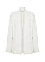 Saco largo tejido color blanco con textura en relieve, corte recto, cuello semi alto, mangas largas y ribete de flecos en el dobladillo, los puños y el cuello.