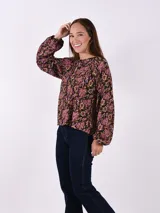 Blusa estampada con flores en tonos rosa, negro y verde. Tiene cuello redondo con abertura en forma de lágrima y mangas largas con puños elásticos.