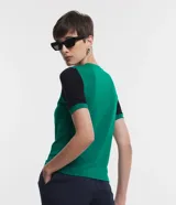 Blusa de viscosa con cuello redondo y mangas cortas. Presenta un diseño de bloques de color contrastantes, con cuerpo en tono malva y mangas en color negro, destacando por sus recortes asimétricos en la sisa.