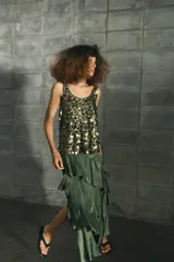 Falda midi de tiro medio color verde oscuro, confeccionada en tejido satinado con volantes en cascada y cierre lateral con cremallera oculta.