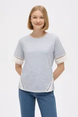 Remera de algodón con estampado de rayas horizontales finas en azul y blanco, cuello redondo a la base, mangas cortas y detalles de encaje calado en los laterales y en los bordes de las mangas.