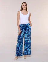 Pantalón de poliéster de corte ancho tipo palazzo y calce relajado, con estampado de hojas en tonos azules, cintura alta elastizada con cordón ajustable y bolsillos laterales.